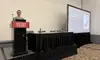 Gavin Rozzi at the NAHRO podium at the Colorado Convention Center in Denver, with the HERF title slide, The Future of Housing, projected on the screen beside him.