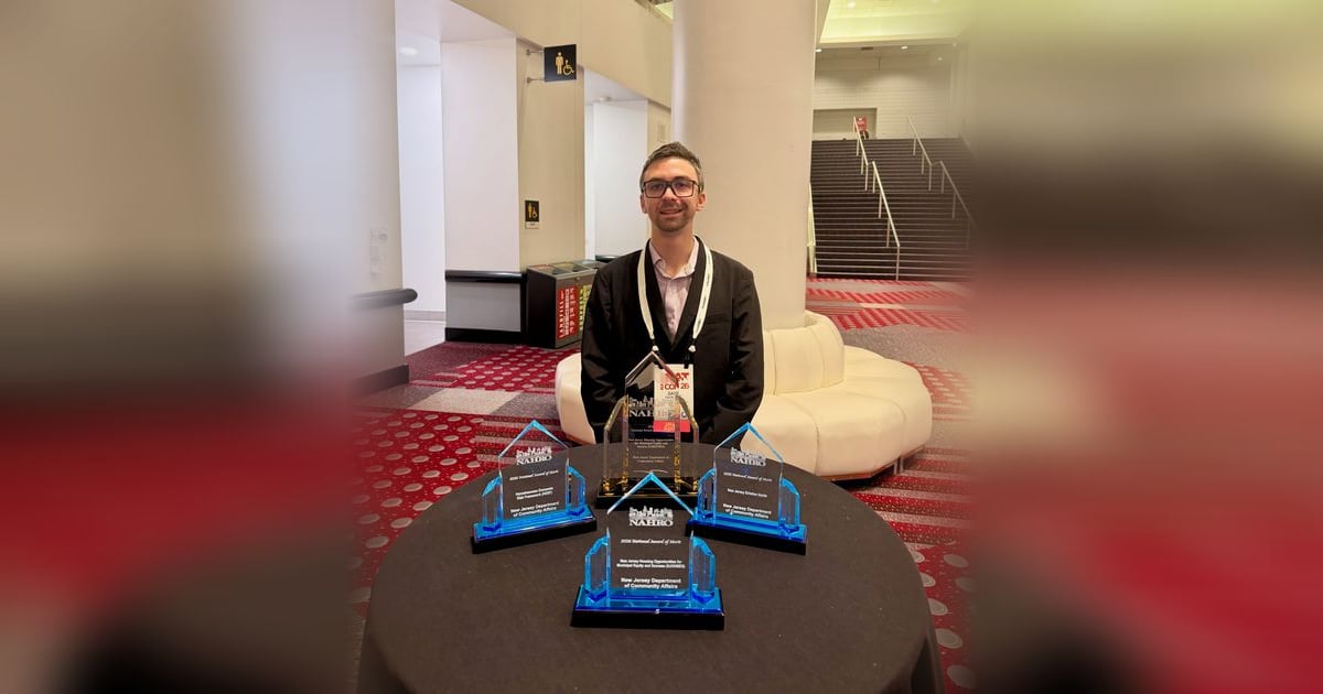 Gavin Rozzi at the 2026 NAHRO National Conference in Denver, standing behind the NAHRO award trophies presented to the New Jersey Department of Community Affairs.